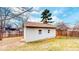 A utility shed with two windows stands in a grassy backyard, bordered by a wooden fence and deciduous trees at 3387 S Pitkin Way, Aurora, CO 80013