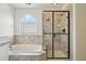 Well-lit bathroom with a glass-door shower, a soaking tub, and a unique window at 4520 Maroon Cir, Broomfield, CO 80023