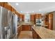 Stylish kitchen with stainless steel refrigerator and appliances, tile backsplash, wood cabinets, and granite countertops at 5531 Fox Meadow Ave, Highlands Ranch, CO 80130