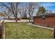 A well-maintained backyard with a green lawn, surrounded by a white fence and mature trees at 5743 Field St, Arvada, CO 80002