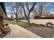Spacious backyard has mature trees, a concrete patio with outdoor seating, plus gravel and grassy areas at 5743 Field St, Arvada, CO 80002