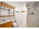Functional bathroom with a shower, wood-look vanity, and ample lighting with a mounted mirror at 7773 Brentwood Ct, Arvada, CO 80005