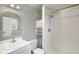 Bright bathroom features a shower with modern fixtures, vanity with arched mirror, and convenient storage at 7773 Brentwood Ct, Arvada, CO 80005