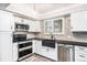 Renovated kitchen with white cabinets, stainless appliances, a black farmhouse sink, and plank flooring at 7773 Brentwood Ct, Arvada, CO 80005