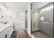 Bathroom featuring double sinks, quartz countertops, glass shower and wood look floors at 5614 Riverbend Ave, Firestone, CO 80504