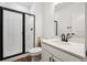 Modern bathroom featuring a glass door shower, single sink vanity with white counter and black fixtures at 5614 Riverbend Ave, Firestone, CO 80504