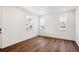 Bright living room featuring hardwood floors and three windows offering plenty of natural light at 5614 Riverbend Ave, Firestone, CO 80504