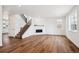 Open living room featuring hardwood floors, stairs to second floor, and modern fireplace at 5614 Riverbend Ave, Firestone, CO 80504