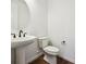Clean powder room featuring a pedestal sink, a round mirror, and modern fixtures at 5614 Riverbend Ave, Firestone, CO 80504