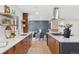 Spacious kitchen area featuring wood cabinets, stone countertops, stainless hood vent, and an open view to living area at 3775 S Forest Way, Denver, CO 80237