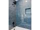 Detailed view of the tub and shower with modern tile surround and recessed storage in the shower at 3775 S Forest Way, Denver, CO 80237