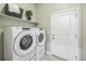 A well-equipped laundry room featuring a Whirlpool washer and dryer with storage shelves and a door to the outside at 12574 Lake View St, Longmont, CO 80504