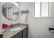 Bathroom featuring an oval sink, vanity, granite countertops, round mirror and a large window at 9742 Burntwood Ct, Highlands Ranch, CO 80126