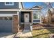 Charming front entrance with brick accents, gray siding, and steps leading to the front door at 9742 Burntwood Ct, Highlands Ranch, CO 80126