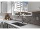 Bright kitchen featuring a stainless sink, faucet, white countertops, and decorative gray backsplash tiles at 9742 Burntwood Ct, Highlands Ranch, CO 80126