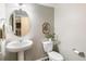 Half bathroom features a pedestal sink, round mirror, and modern toilet at 11761 Cord Grass Way, Parker, CO 80138
