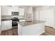 Well-lit kitchen boasts stainless steel appliances, white cabinets, a center island, and wood-look flooring at 2986 Oxley St, Strasburg, CO 80136