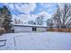 Winter backyard scene featuring a white house, bare trees, and a wooden fence under a cloudy sky at 3091 S Krameria St, Denver, CO 80222