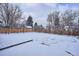 Spacious backyard covered in snow, framed by bare trees and a wooden fence in a winter setting at 3091 S Krameria St, Denver, CO 80222