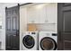 Convenient laundry room showcasing a washer, dryer, overhead storage, and stylish sliding door at 3091 S Krameria St, Denver, CO 80222