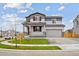 Charming two-story home featuring gray and white siding, a covered front porch, and manicured landscaping at 12353 E 101St Pl, Commerce City, CO 80022