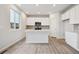 Modern kitchen features white cabinets, an island with sink, and stainless steel appliances with bright, natural light at 12353 E 101St Pl, Commerce City, CO 80022