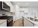 Open kitchen showcasing stainless steel appliances, modern cabinets, and a kitchen island with a sink at 12353 E 101St Pl, Commerce City, CO 80022