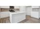 Bright kitchen features a kitchen island, white cabinets, stainless steel appliances, and wood flooring at 12353 E 101St Pl, Commerce City, CO 80022