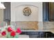 Close-up of cooktop and floral wreath with earth-toned backsplash and dark wood cabinets at 1673 Morningview Ln, Castle Rock, CO 80109