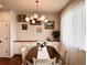 Dining room with wooden table, white chairs, modern light fixture, and picture frame decor at 18145 E Weaver Ave, Aurora, CO 80016