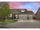 Charming home featuring a manicured lawn, a three-car garage, and a stone and siding facade against a backdrop of a vibrant sunset sky at 20162 E 53Rd Pl, Denver, CO 80249