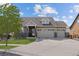 Charming home featuring a manicured lawn, a three-car garage, and a stone and siding facade under a sunny blue sky at 20162 E 53Rd Pl, Denver, CO 80249