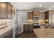 Gourmet kitchen with stainless steel appliances, granite countertops, tile backsplash, and rich wood cabinets at 20162 E 53Rd Pl, Denver, CO 80249