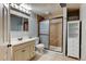 A full bathroom featuring a glass door shower, a cabinet, and a large vanity mirror at 12135 Elizabeth St, Thornton, CO 80241