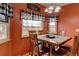Dining area with wooden table and chairs, three windows with Buffalo check curtains, and warm, cozy colors at 12135 Elizabeth St, Thornton, CO 80241