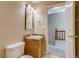 Cozy bathroom with wooden vanity, framed mirror, and access to the hallway and second floor at 2035 Overland Dr, Brighton, CO 80601
