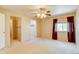 Bright bedroom with neutral carpet, ceiling fan, a window with curtains and multiple doorways at 2035 Overland Dr, Brighton, CO 80601