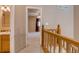 Hallway with wooden banister leading to a carpeted bedroom with ceiling fan, and an adjacent bathroom at 2035 Overland Dr, Brighton, CO 80601