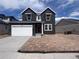 New two-story home featuring a two-car garage, red front door, dark siding, and unfinished front yard at 4284 Ridgewalk Pt, Castle Rock, CO 80108