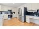 Bright kitchen with stainless steel refrigerator, white cabinets, and wood floors at 11 Canongate Ln, Highlands Ranch, CO 80130