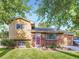 Charming two-story home featuring a brick facade, manicured lawn, mature trees, and a welcoming red front door at 6664 Gray St, Arvada, CO 80003