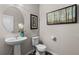 Stylish powder room with a pedestal sink, decorative mirror, and modern fixtures at 2405 Horse Shoe Cir, Fort Lupton, CO 80621
