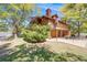 Charming exterior view showcasing the home's balcony, brick accents, mature trees and a lush green lawn at 1810 Youngfield Ct # A, Golden, CO 80401