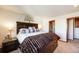 Warm bedroom featuring a king bed with decorative headboard and a glimpse into an attached bath at 1810 Youngfield Ct # A, Golden, CO 80401
