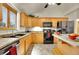 Kitchen with a sink and window, tile floors, wooden cabinets and black appliances at 2616 E Egbert St, Brighton, CO 80601