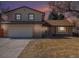 Charming brick and siding home at twilight featuring an attached garage, mature trees, and well-maintained lawn at 6527 S Ammons Ct, Littleton, CO 80123