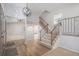 Inviting foyer with hardwood floors, coat closet, elegant staircase, and modern light fixture at 6527 S Ammons Ct, Littleton, CO 80123