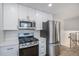 Modern kitchen with stainless steel appliances, white cabinets, quartz countertops, and wood-look floors at 6527 S Ammons Ct, Littleton, CO 80123