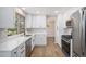 Well-lit kitchen featuring white cabinets, stainless steel appliances, quartz countertops, and wood-look floors at 6527 S Ammons Ct, Littleton, CO 80123