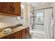 Bathroom with dark wood cabinets, granite countertops, a sink, a toilet, and a shower-tub combo at 2541 Cherry St, Denver, CO 80207